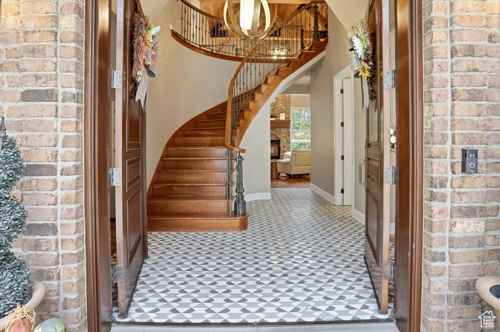 Entrance foyer featuring brick wall, stairs, and a chandelier