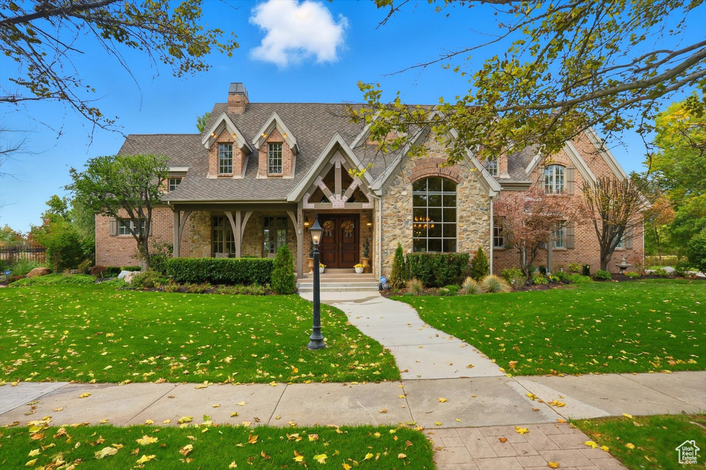 View of front of property with a front lawn, a porch, a shingled roof, and a chimney