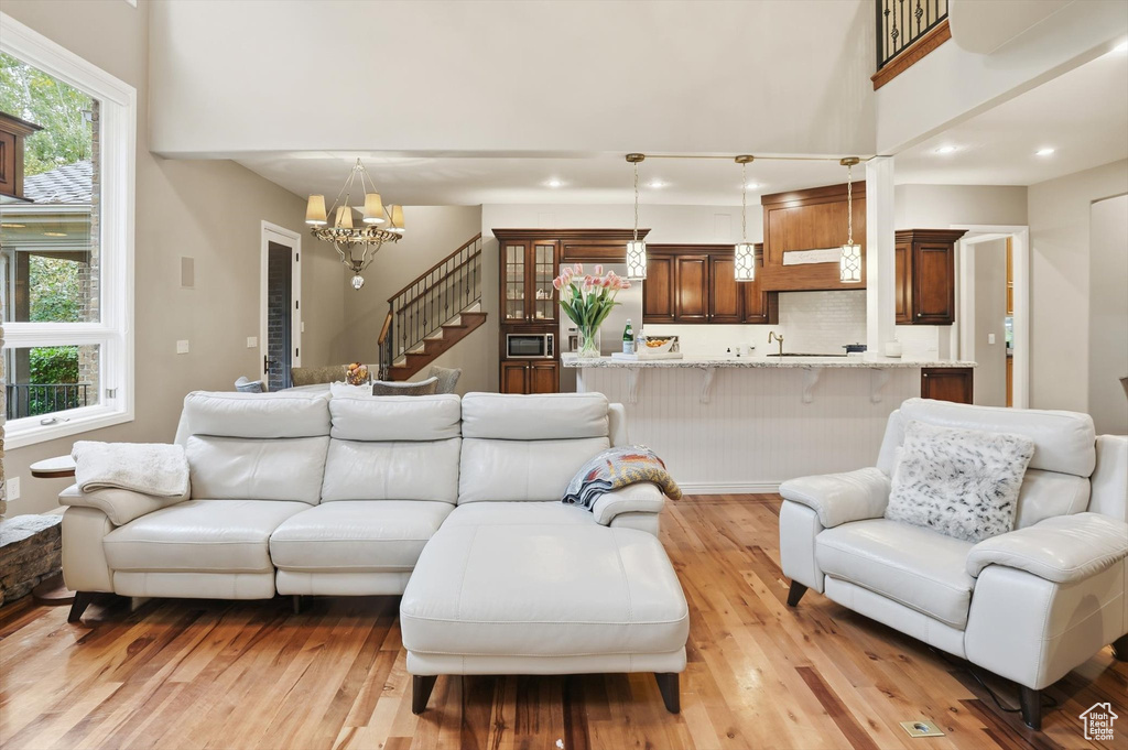 Living room featuring stairs, light wood-type flooring, recessed lighting, plenty of natural light, and a chandelier