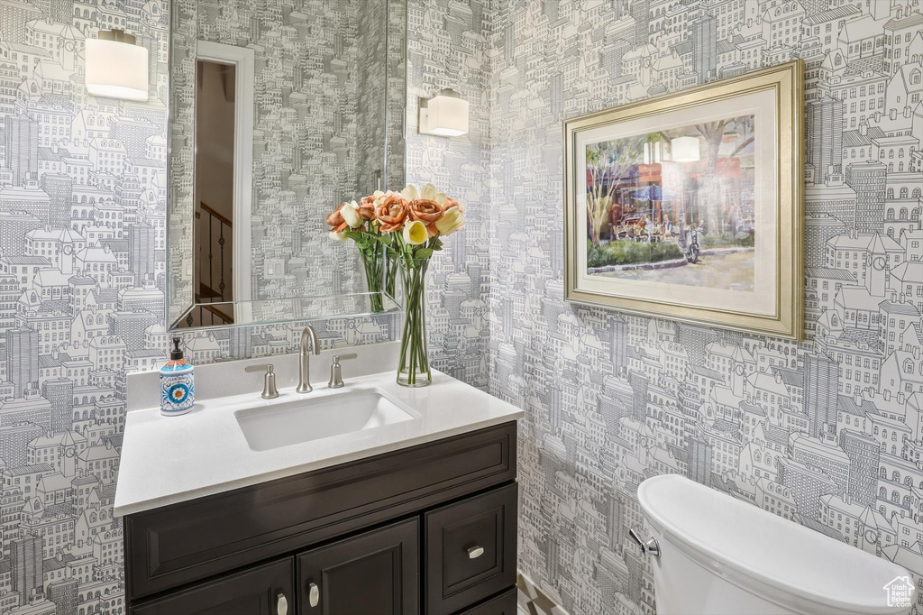 Half bath with wallpapered walls and vanity