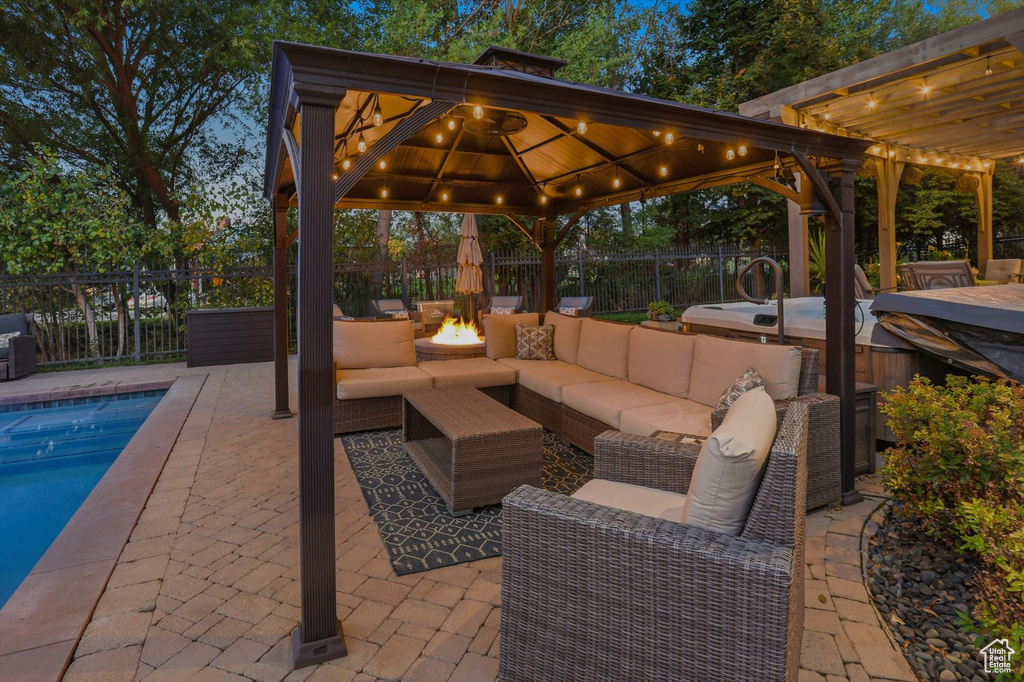 Fenced backyard with a patio area, an outdoor living space with a fire pit, an outdoor hot tub, and a gazebo
