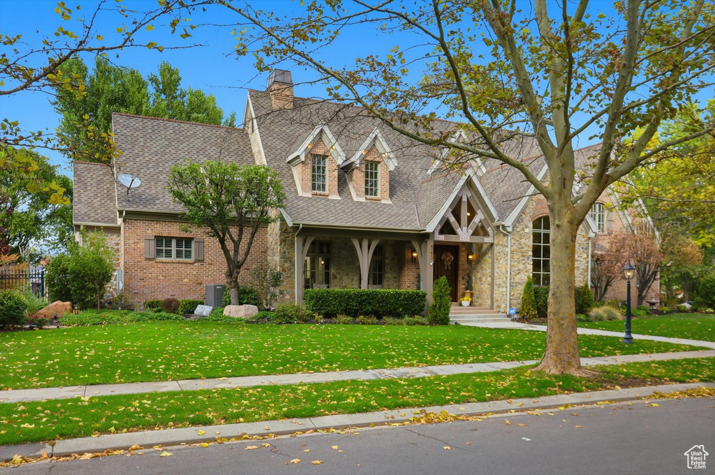 View of front of home with a porch, a front yard, and a shingled roof