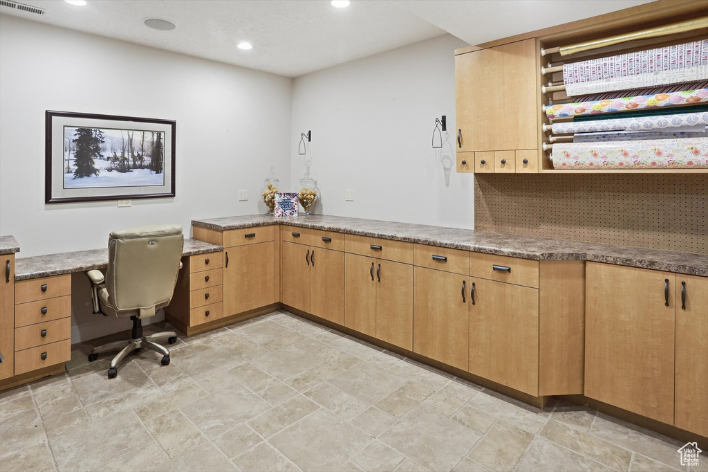 Unfurnished office featuring recessed lighting, built in desk, and light stone finish flooring
