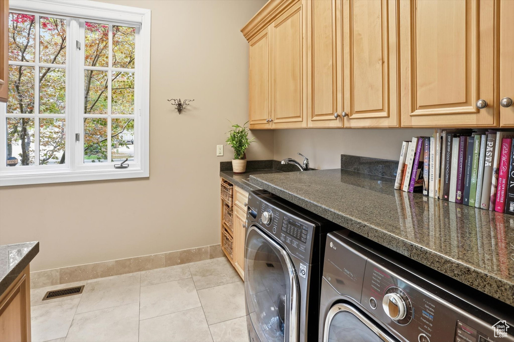 Laundry room with cabinet space, light tile patterned flooring, and washing machine and clothes dryer