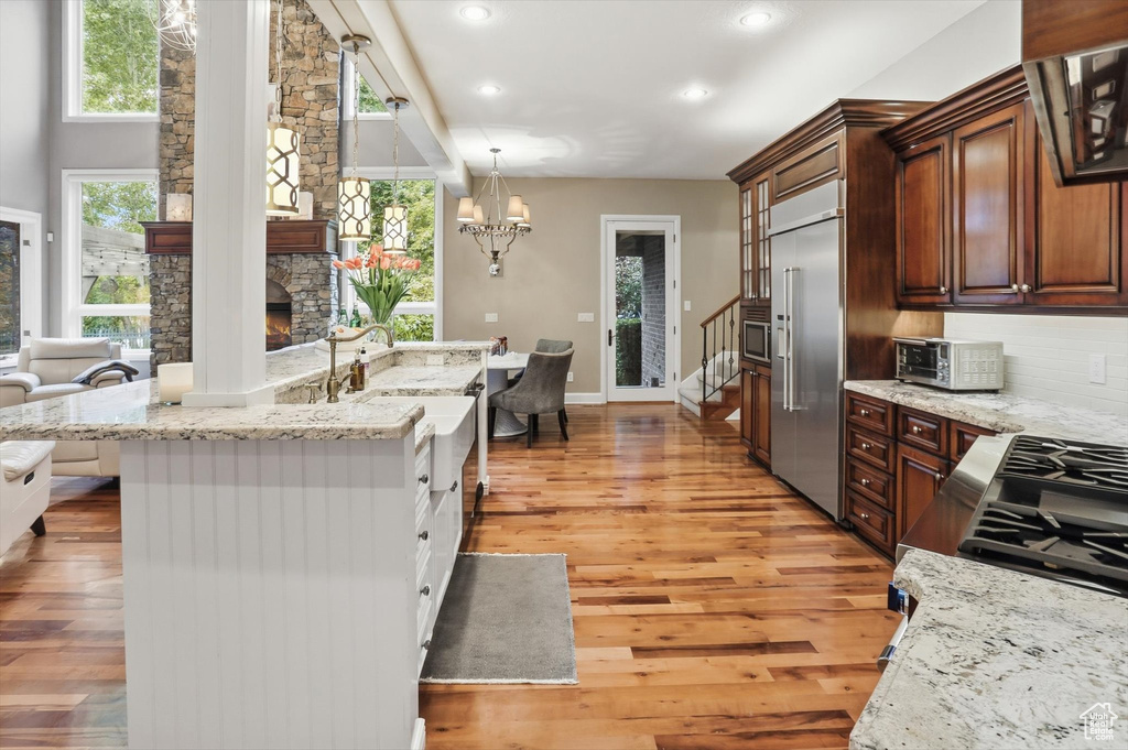 Kitchen featuring light stone countertops, stainless steel appliances, decorative light fixtures, tasteful backsplash, and recessed lighting