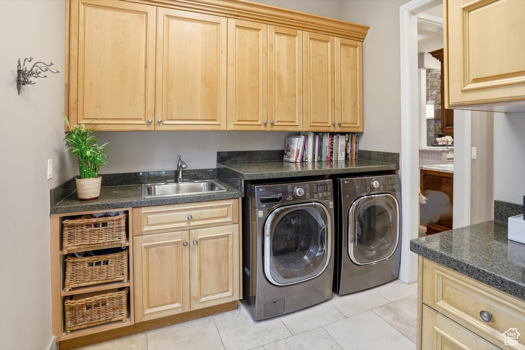 Laundry room featuring independent washer and dryer, light tile patterned floors, and cabinet space