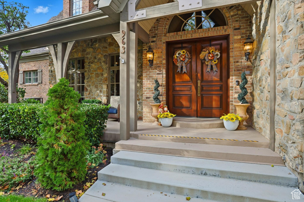 Doorway to property featuring a porch, stone siding, and brick siding