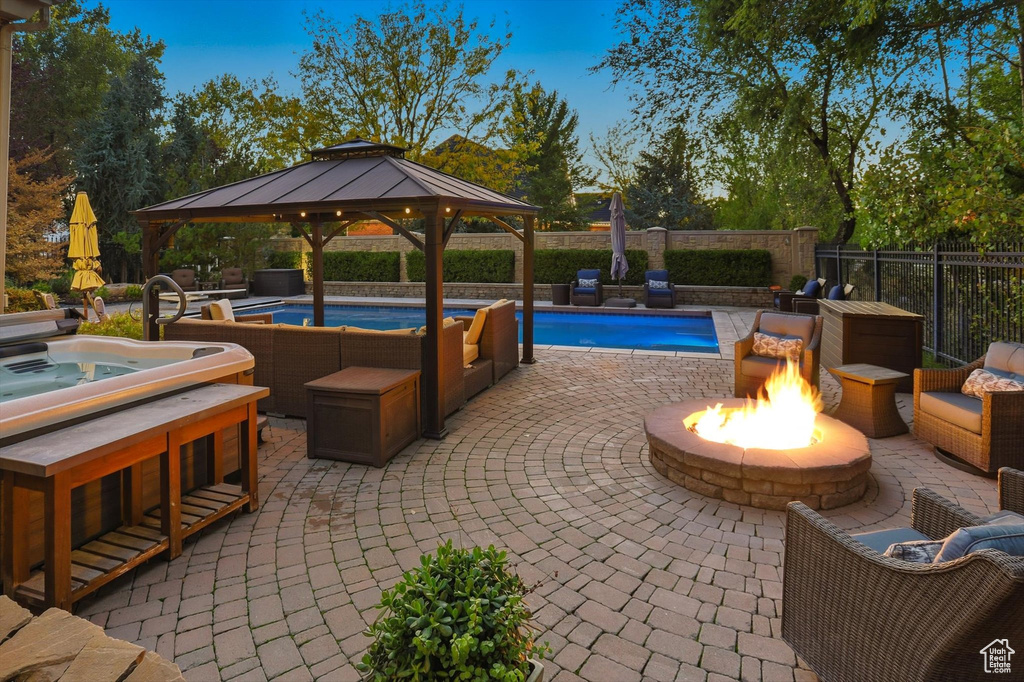 View of pool featuring a gazebo, an outdoor hot tub, a patio, and a fenced backyard