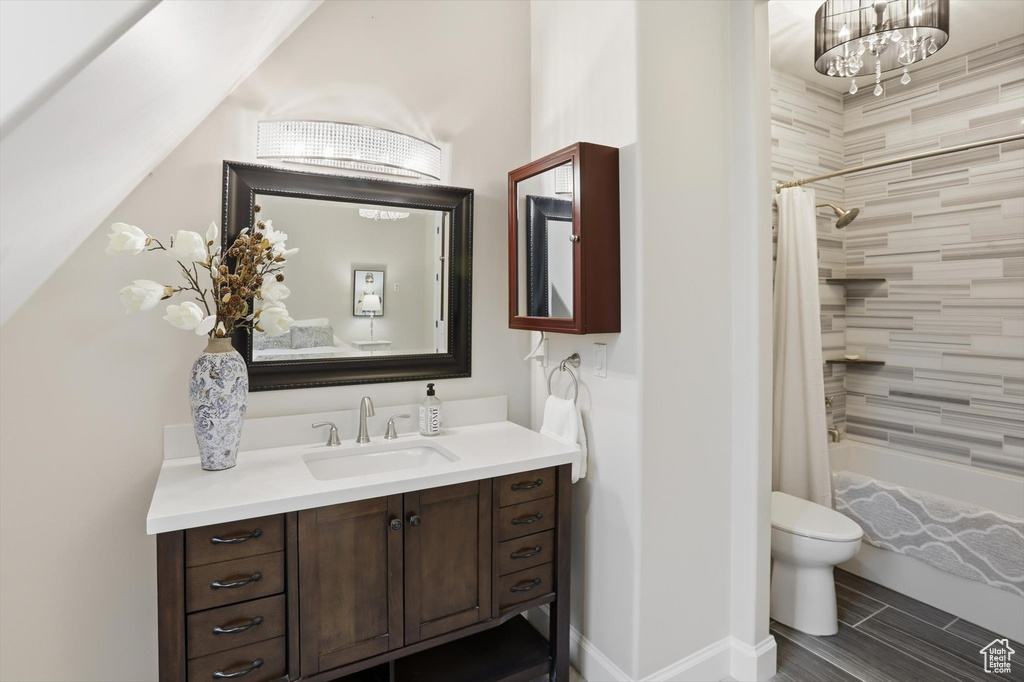 Bathroom featuring vanity, shower / tub combo with curtain, and wood finish floors