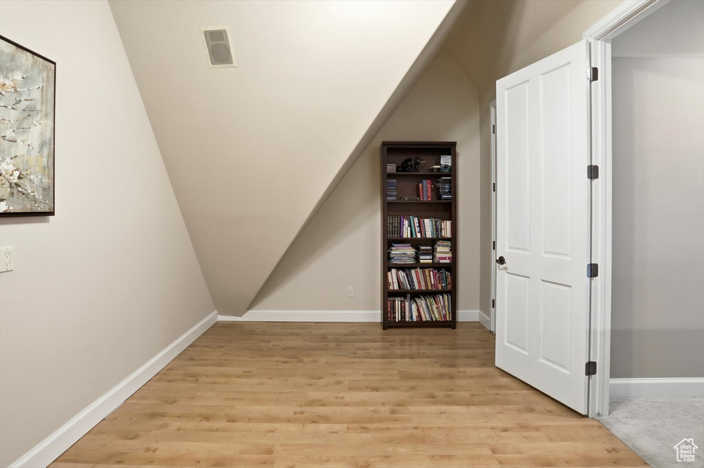 Additional living space with light wood-style floors and lofted ceiling