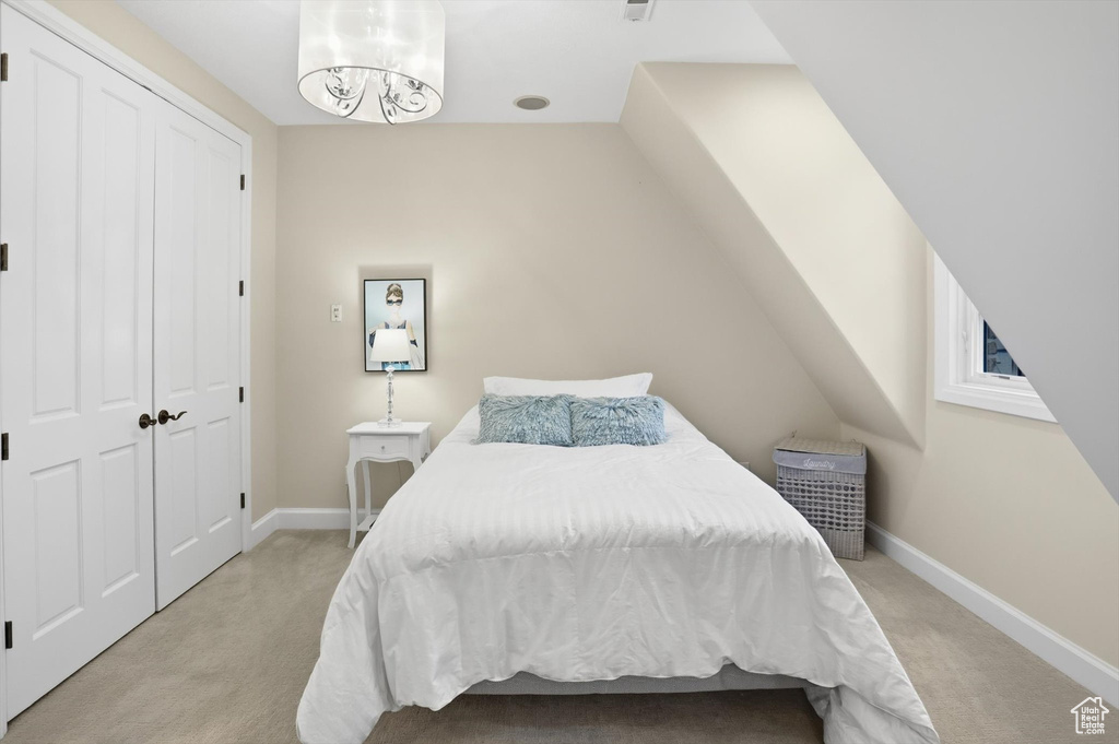 Bedroom featuring light colored carpet and a chandelier