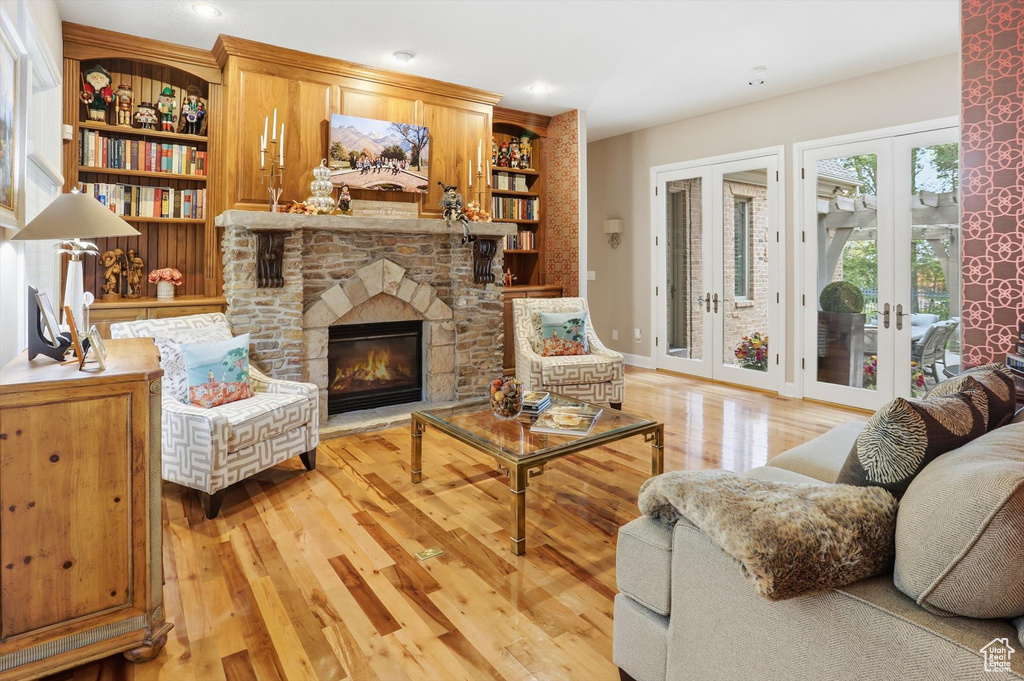 Living area with a fireplace, built in features, french doors, light wood-type flooring, and recessed lighting