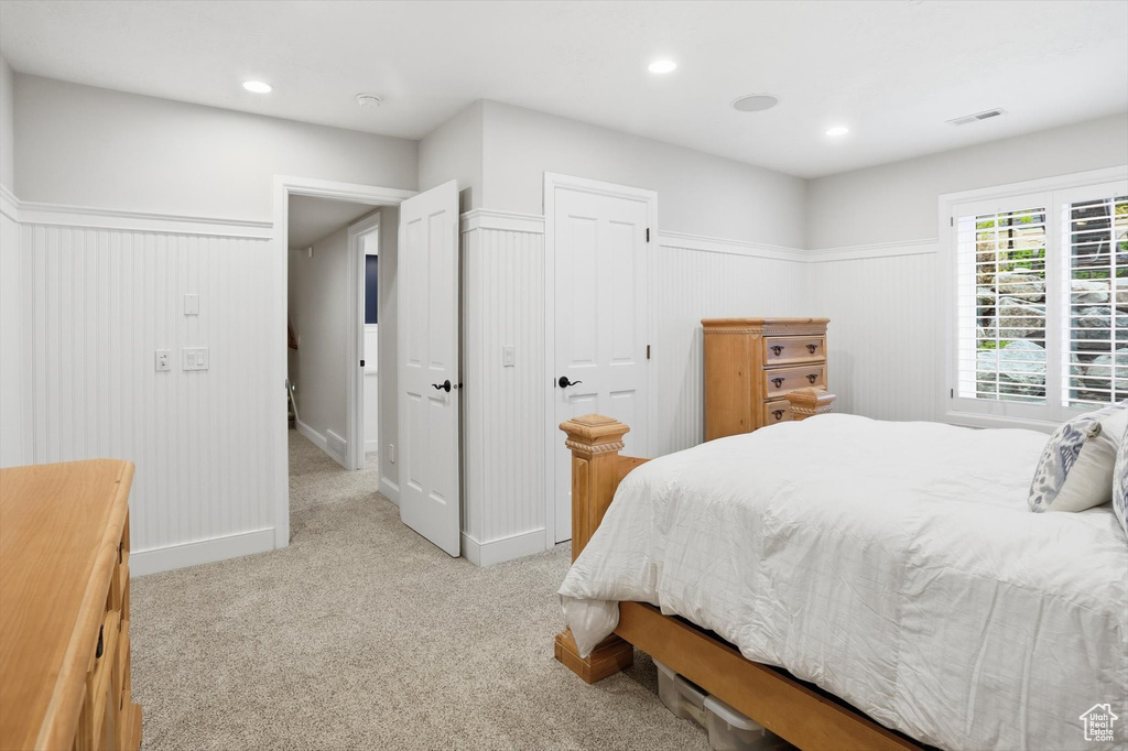 Bedroom with light colored carpet, a closet, wainscoting, recessed lighting, and wooden walls