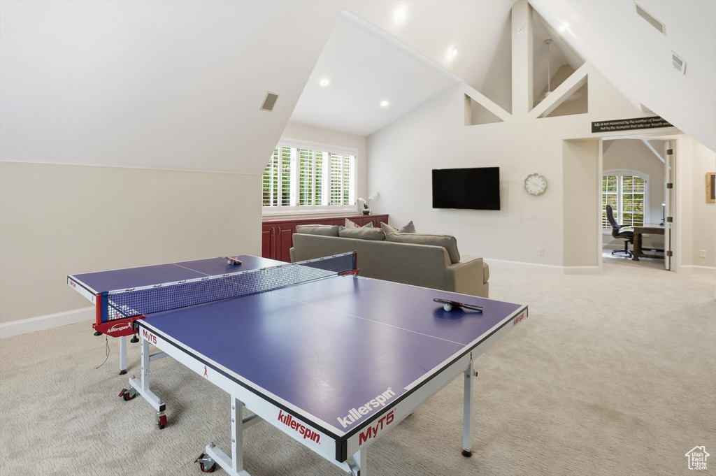 Rec room featuring light colored carpet, high vaulted ceiling, arched walkways, and recessed lighting