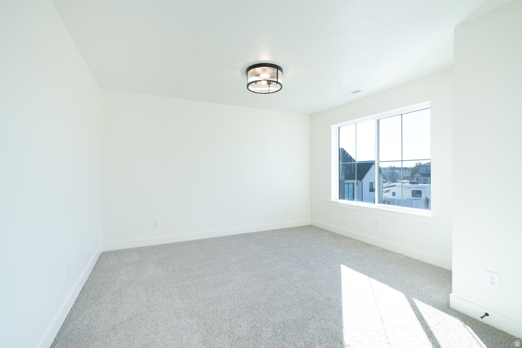 Spare room featuring light colored carpet and baseboards