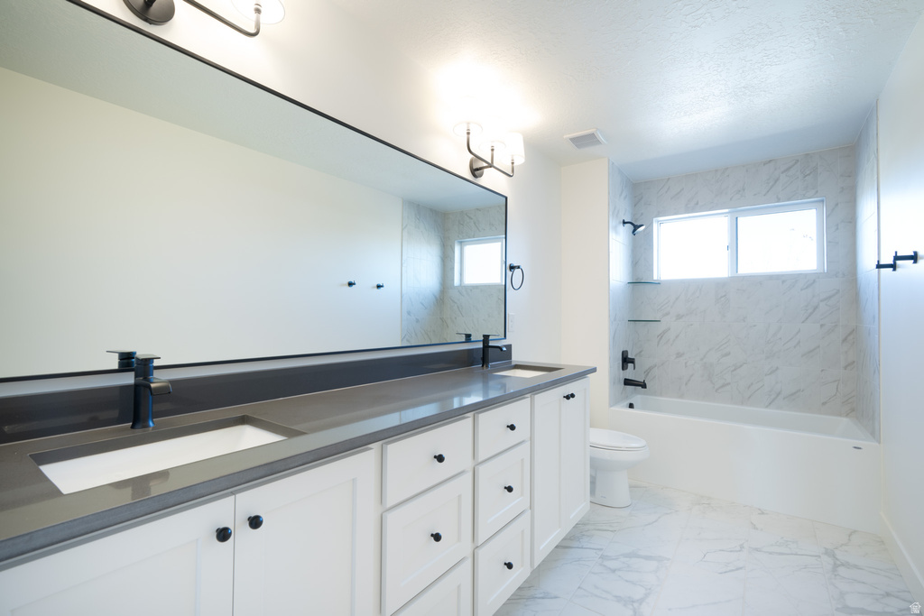 Full bathroom featuring double vanity, shower / tub combination, light marble finish flooring, and a textured ceiling