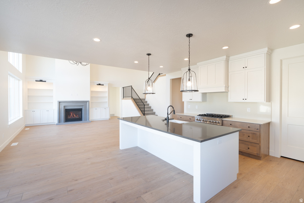 Kitchen with white cabinetry, hanging light fixtures, open floor plan, recessed lighting, and light wood finished floors