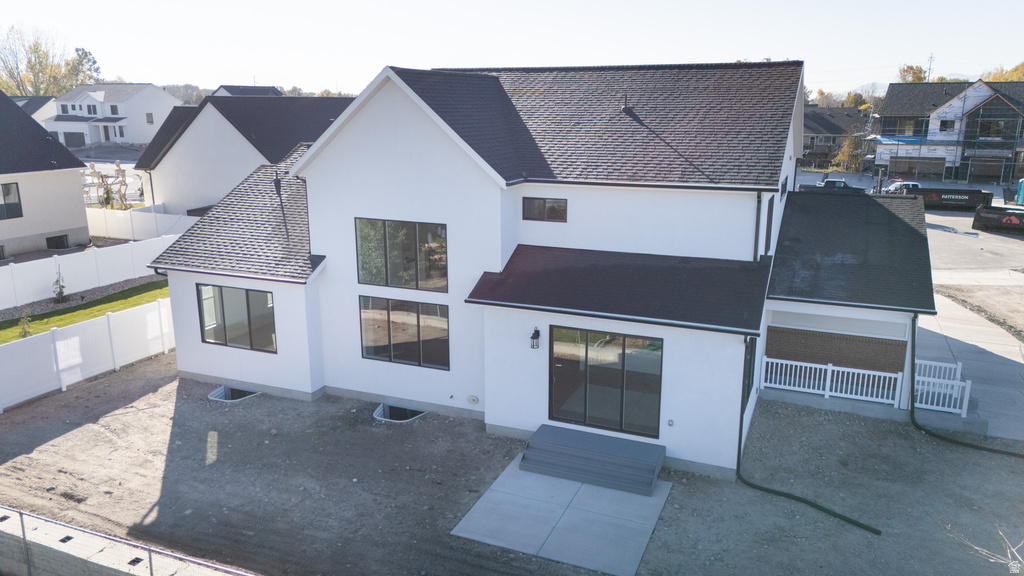 Rear view of house with a residential view, stucco siding, entry steps, and roof with shingles