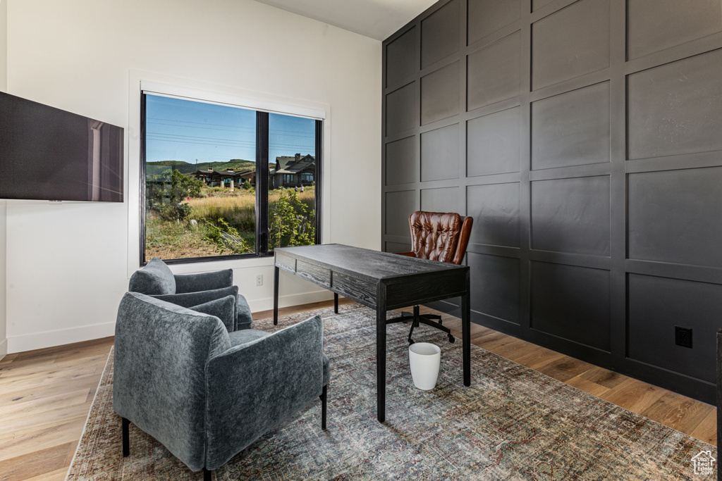 Home office with light wood-style floors and a decorative wall