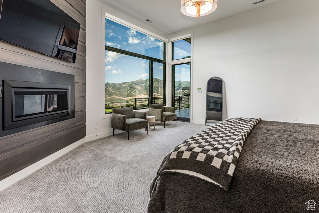 Bedroom featuring expansive windows, a mountain view, light colored carpet, and access to exterior