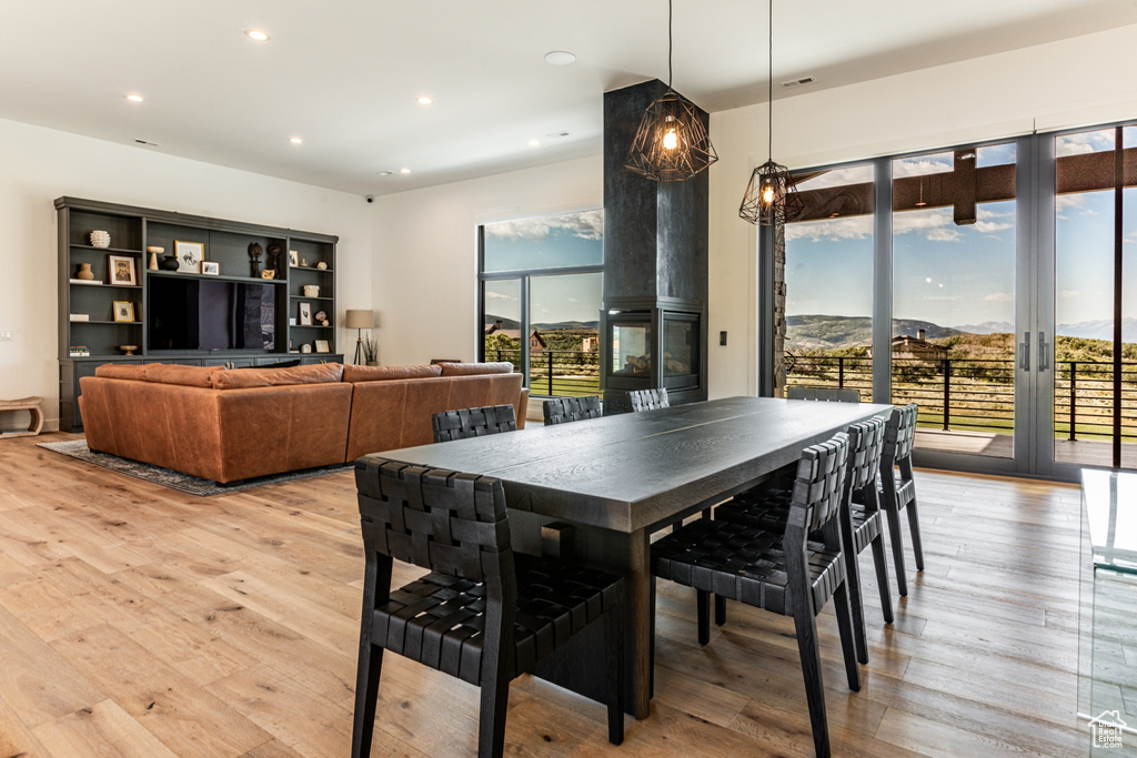 Dining room featuring a multi sided fireplace, light wood finished floors, recessed lighting, and a mountain view