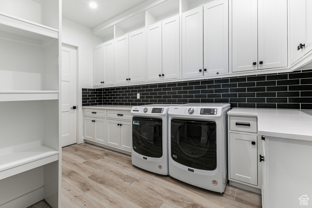 Laundry area featuring light wood-type flooring, independent washer and dryer, and cabinet space