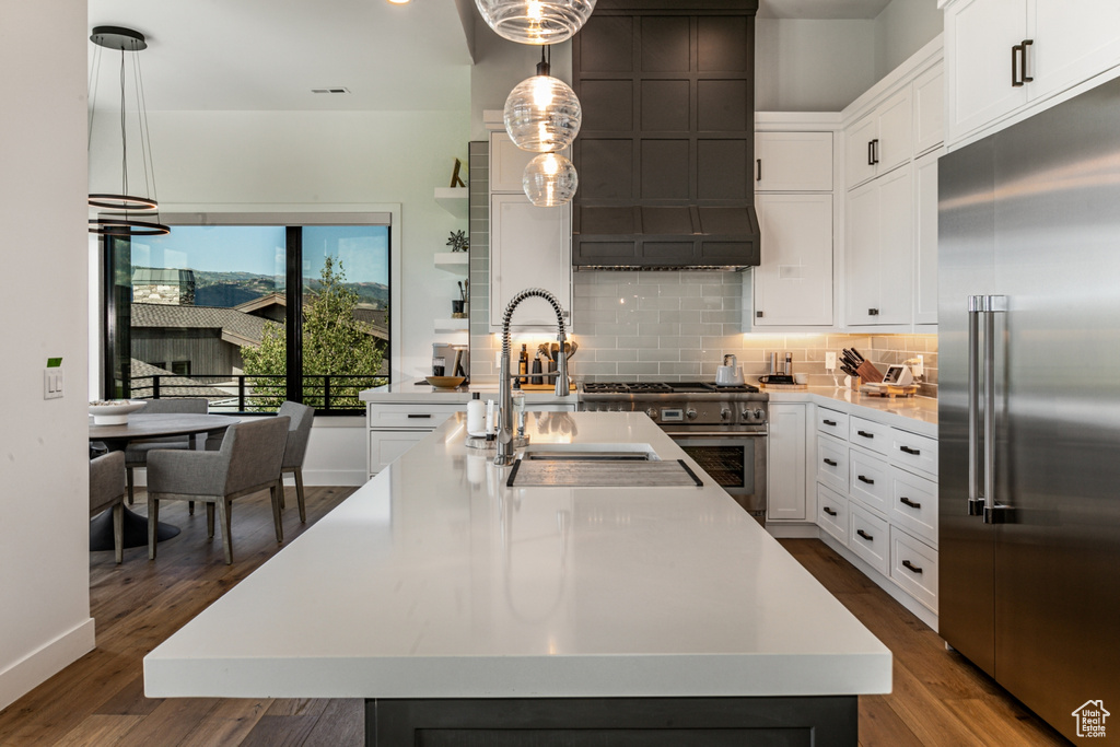 Kitchen with white cabinetry, high quality appliances, decorative backsplash, pendant lighting, and recessed lighting