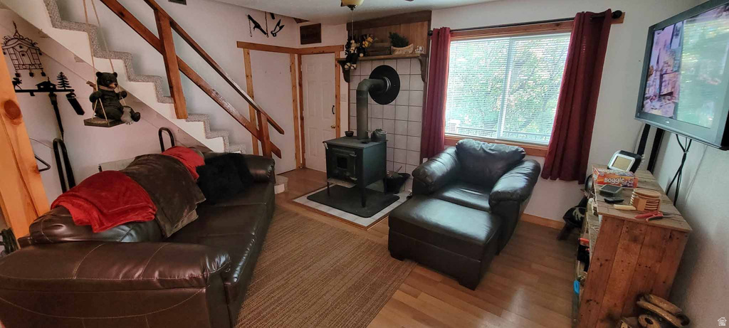 Living room featuring a wood stove, stairway, and wood finished floors