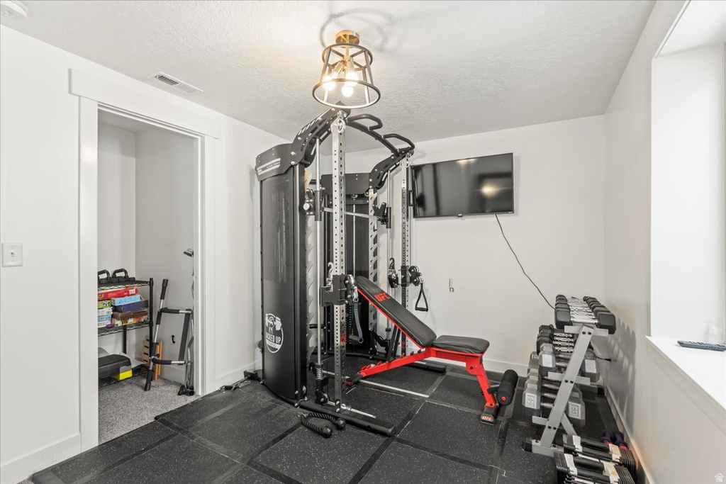 Exercise area featuring rubber floors and a textured ceiling