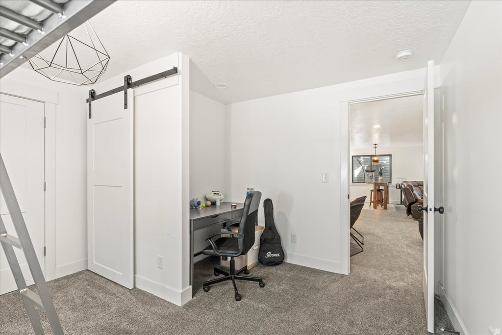Office with carpet flooring, a barn door, and a textured ceiling