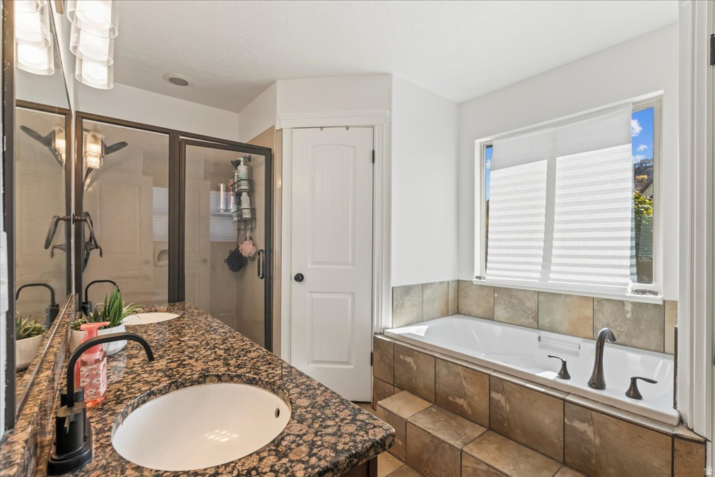 Full bathroom featuring double vanity, a garden tub, and a shower stall