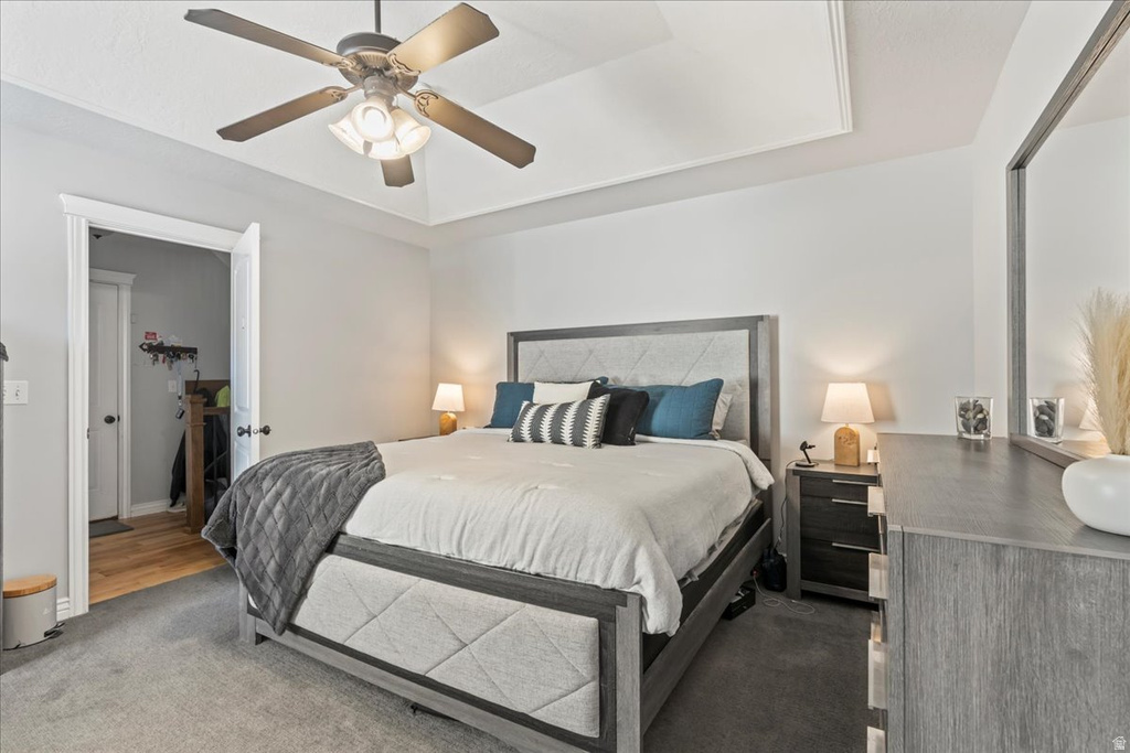 Bedroom featuring a raised ceiling, carpet flooring, and ceiling fan