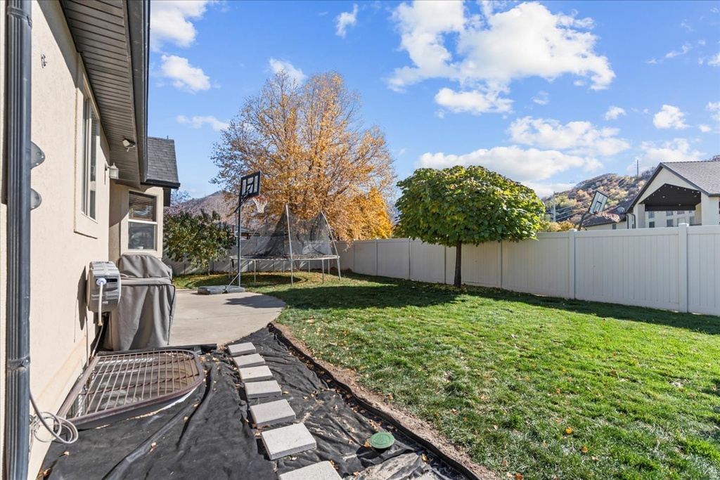Fenced backyard with a trampoline and a patio