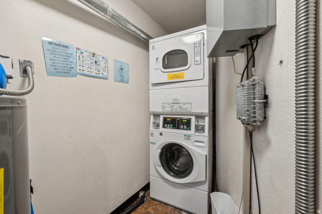 Laundry room featuring stacked washer / drying machine, water heater, and electric water heater