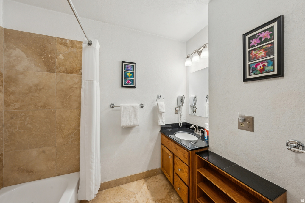 Full bath featuring shower / tub combo with curtain, vanity, and light tile patterned floors