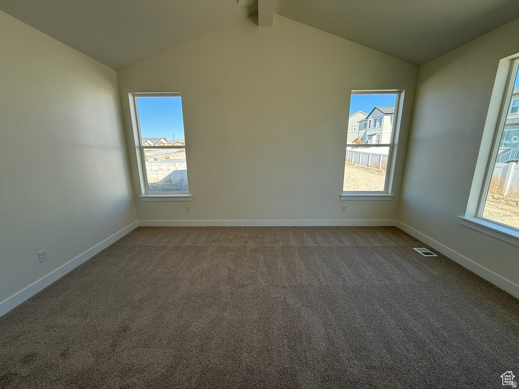 Empty room featuring dark colored carpet and plenty of natural light