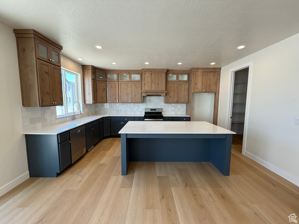 Kitchen with tasteful backsplash, a center island, appliances with stainless steel finishes, glass insert cabinets, and recessed lighting