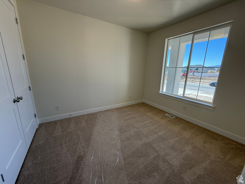 Empty room featuring light colored carpet and baseboards