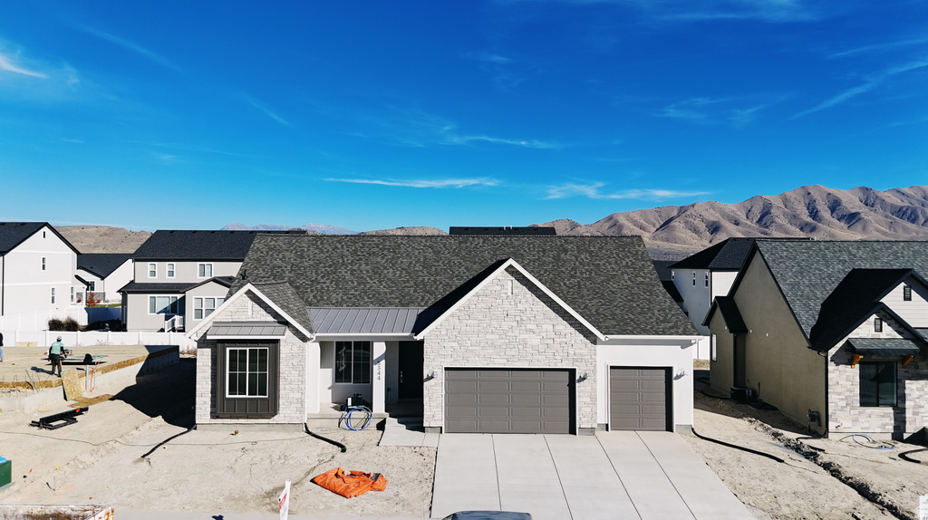 View of front of home featuring stone siding, a mountain view, a standing seam roof, concrete driveway, and covered porch
