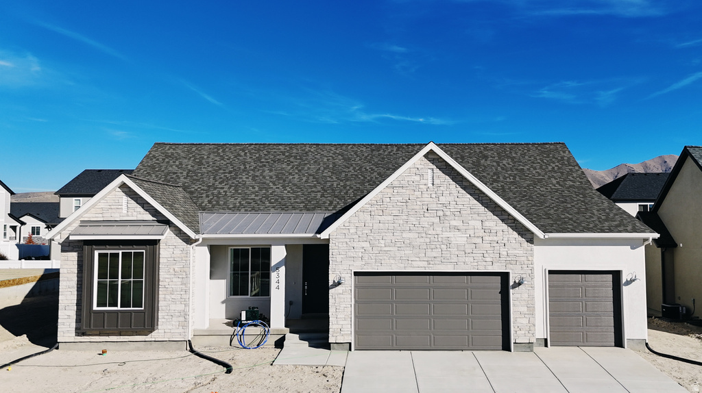 View of front of house with a porch, a garage, concrete driveway, stone siding, and a shingled roof