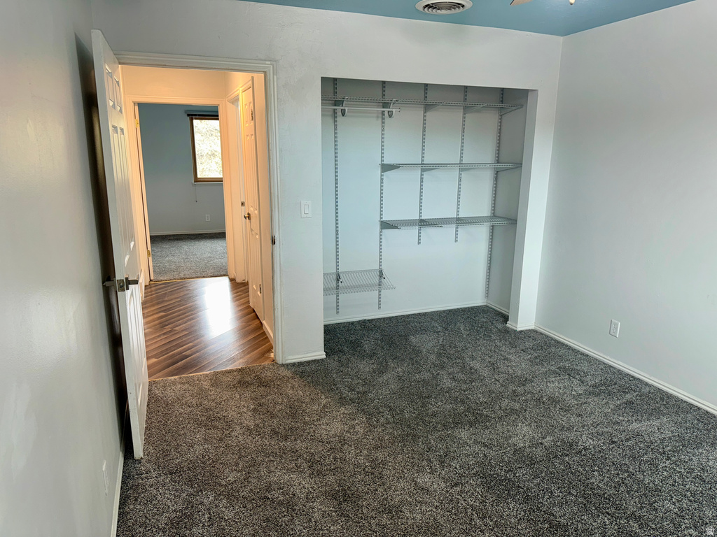 Unfurnished bedroom featuring dark carpet and a closet