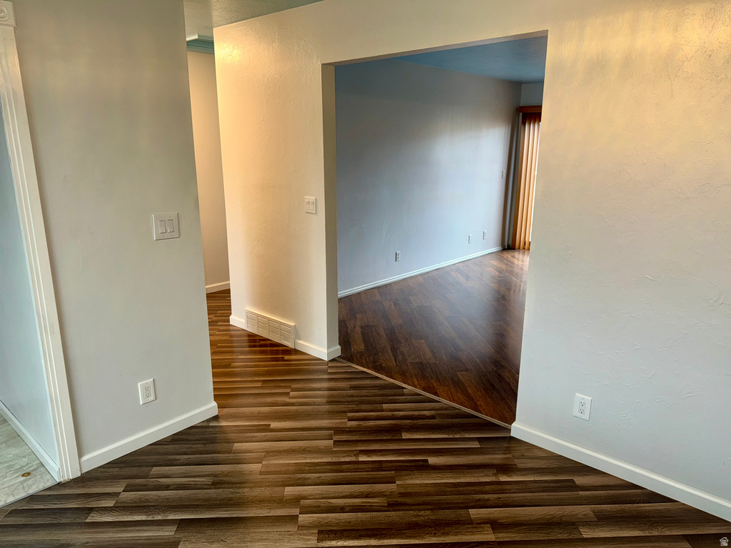Corridor featuring a textured wall and dark wood-style floors