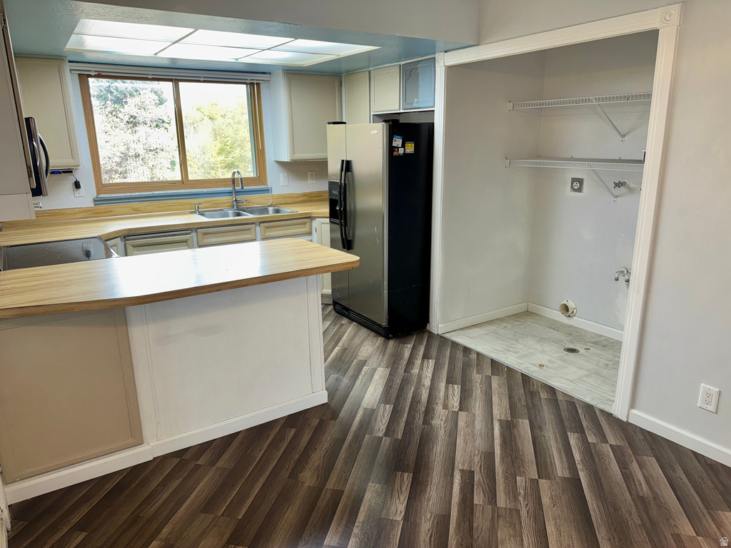 Kitchen with light countertops, appliances with stainless steel finishes, a peninsula, dark wood-style floors, and white cabinets