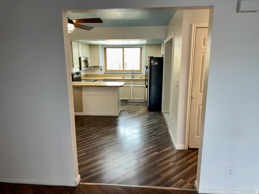 Kitchen with light countertops, stainless steel appliances, dark wood-style floors, white cabinetry, and a peninsula