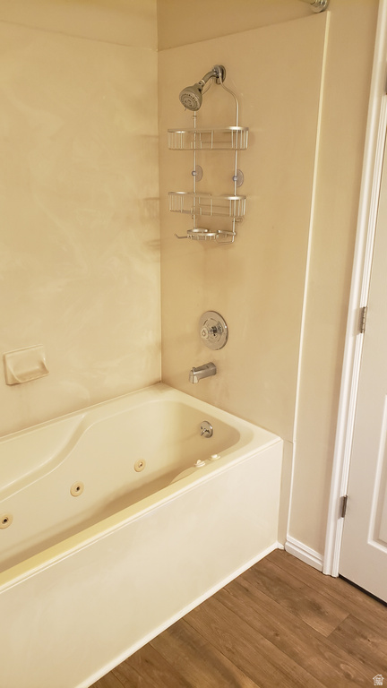 Bathroom featuring a combined bath / shower with jetted tub and dark wood-style floors