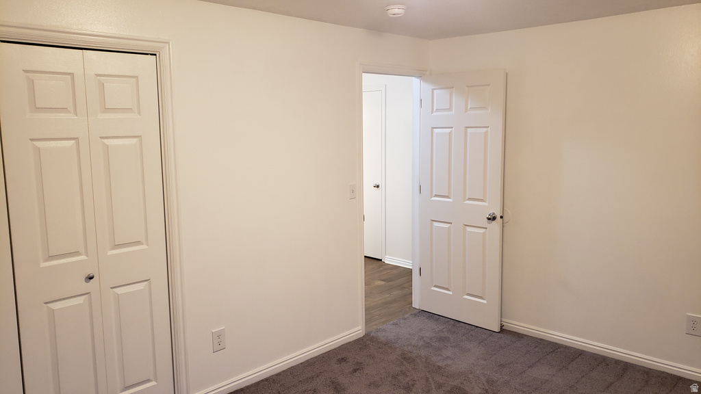 Unfurnished bedroom featuring dark colored carpet and a closet