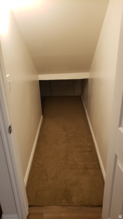 Hallway featuring carpet and vaulted ceiling