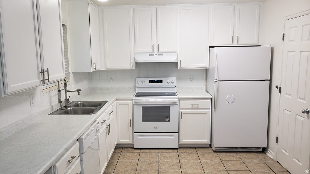 Kitchen with white appliances, tasteful backsplash, light countertops, and white cabinets