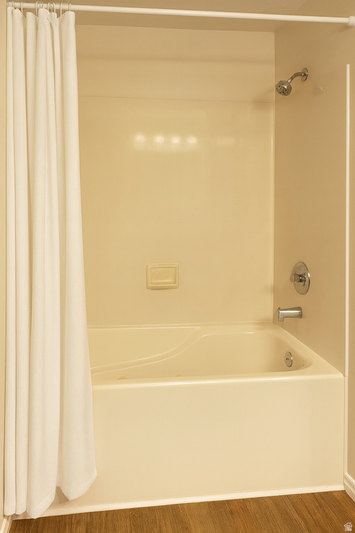 Full bath featuring shower / bath combo with shower curtain and wood finished floors