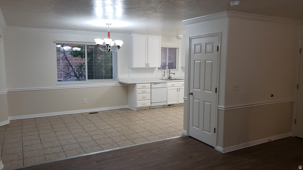 Kitchen with crown molding, light countertops, white cabinetry, a textured ceiling, and dishwasher